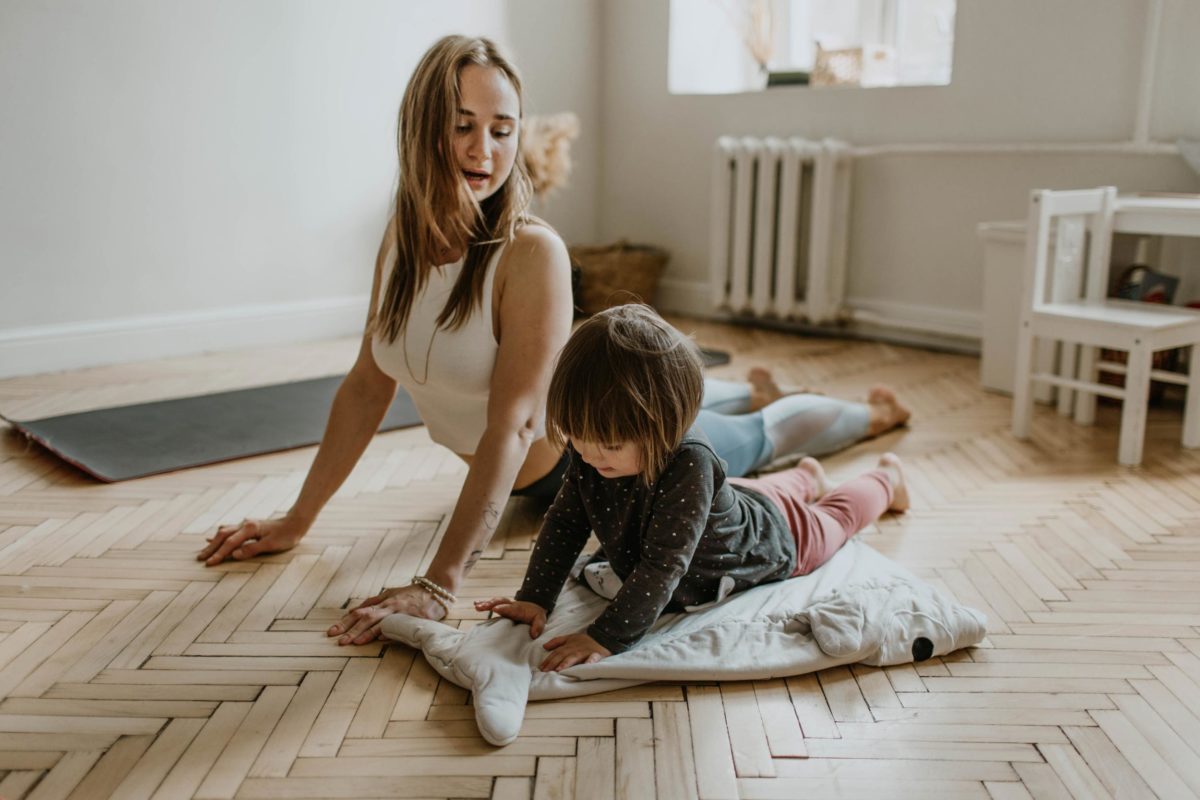 A woman doing yoga wit her daughter in their front room